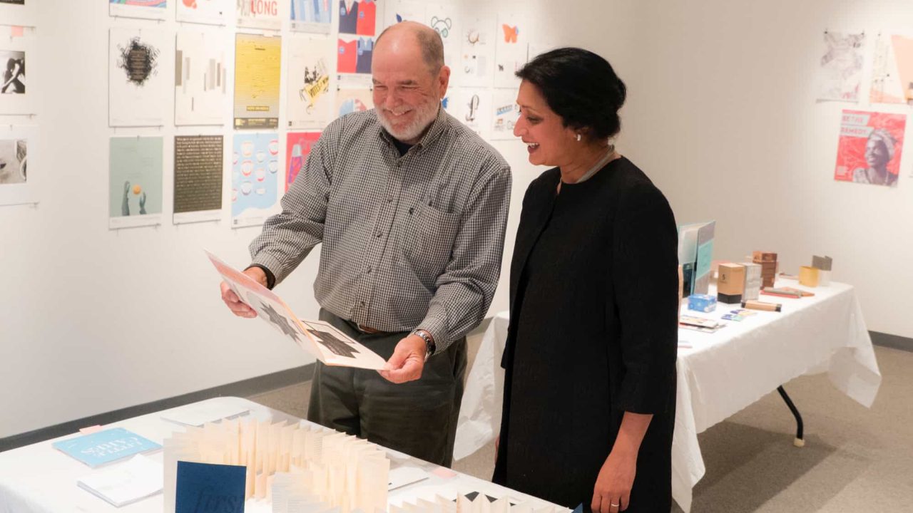 Dr. Vini Nathan speaking to School Head Clark Lundell about student project at Juried show.