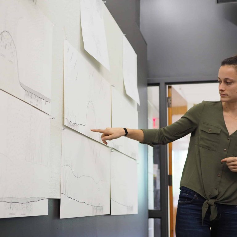 Female Landscape Architecture Student discussing pinned up work at a review