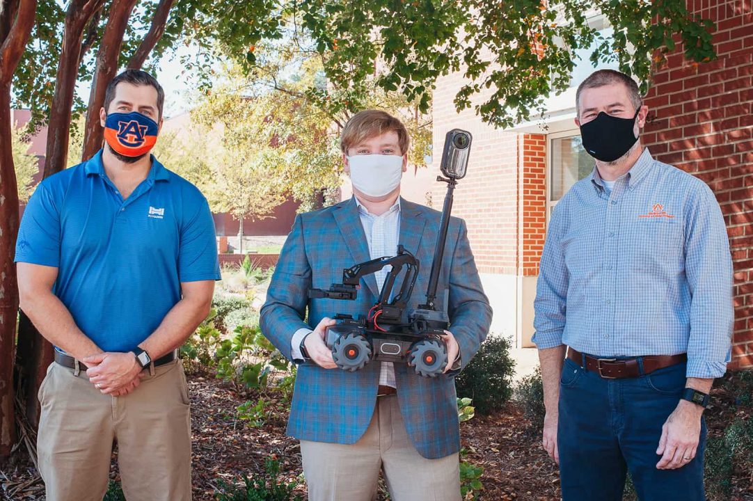 Paul Hedgepath, James Craig, and Jeff Kim pose with robot