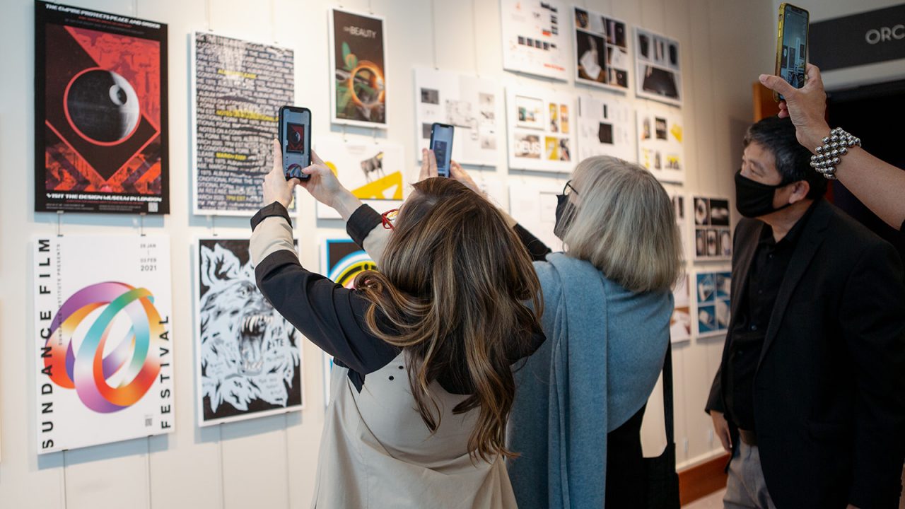 Patrons at the 2021 Graphic Design Juried Show Show interactive with digital design work using smart phones.