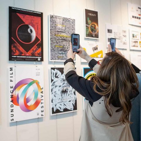 Patrons at the 2021 Graphic Design Juried Show Show interactive with digital design work using smart phones.