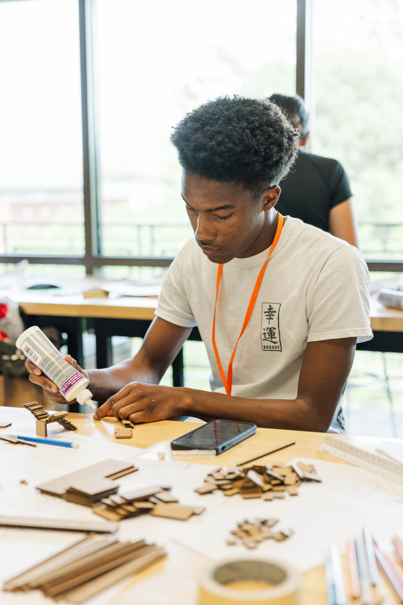 A male student working on an Architecture model with cardboard and glue.