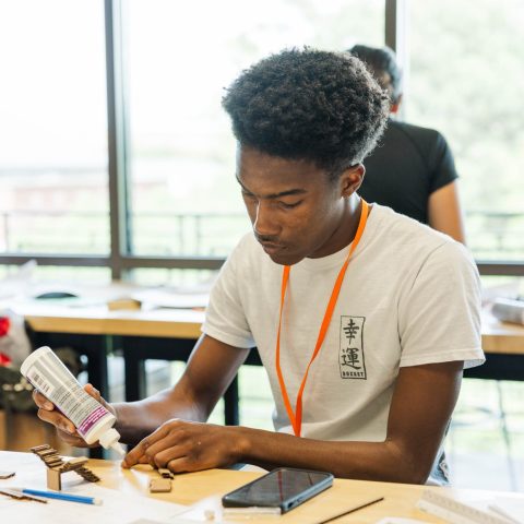 A male student working on an Architecture model with cardboard and glue.