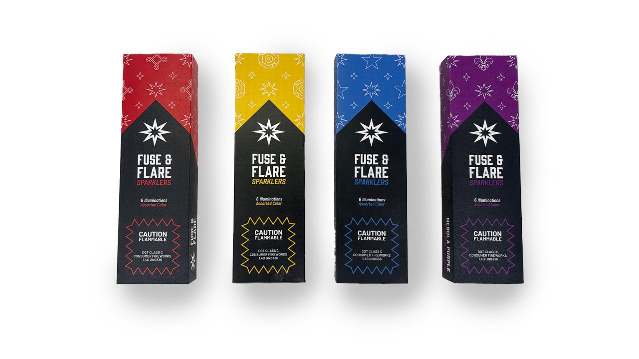 Four Fuse & Flare sparkler boxes in red, yellow, blue, and purple, each with caution labels and geometric designs, are arranged in a row on a white background.