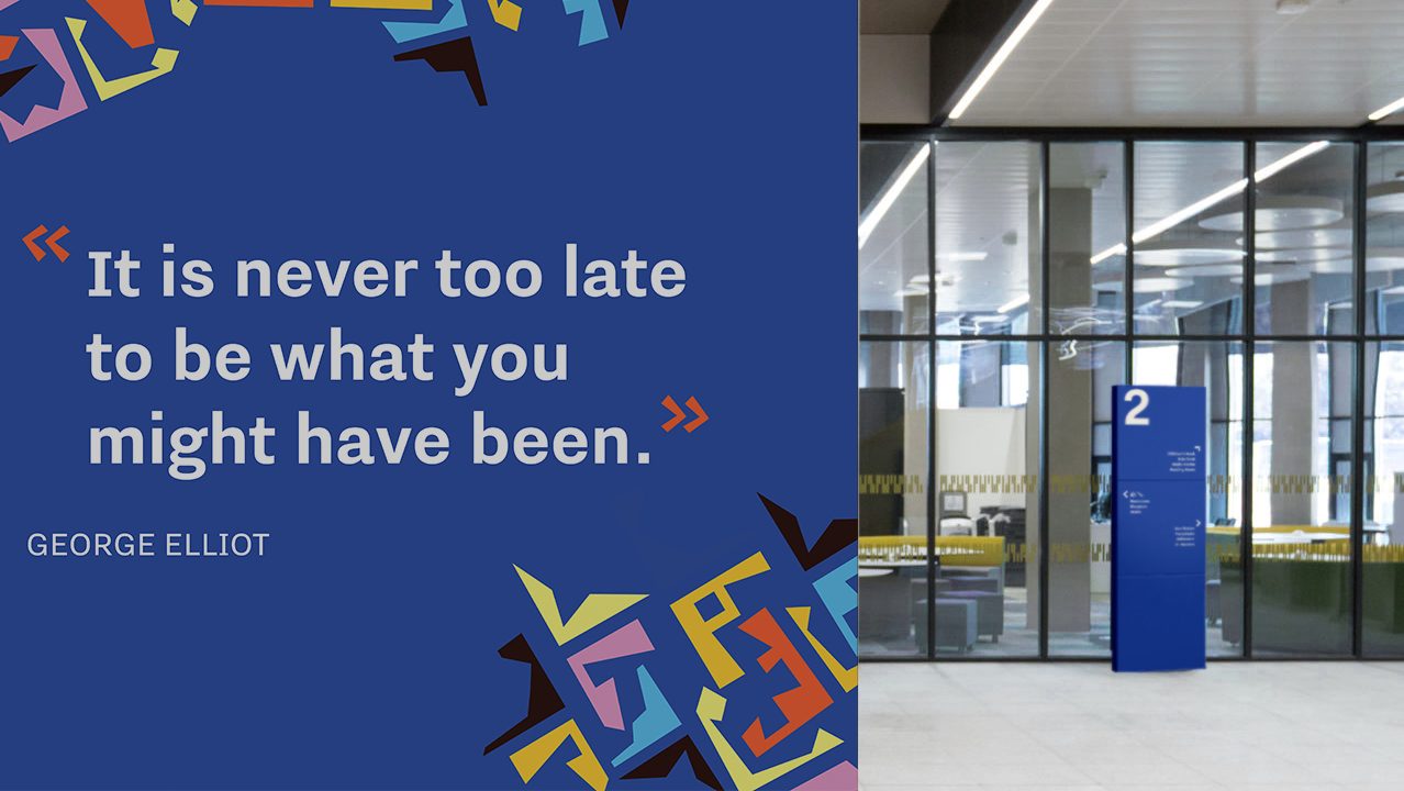 A large blue wall displays the quote, “It is never too late to be what you might have been.” by George Elliot, in a modern building hallway.