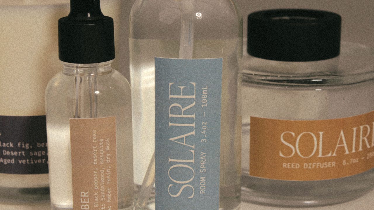 Several bottles and jars of home fragrance products, including room spray and reed diffuser, labeled with the brand SOLAIRE, are arranged closely together.