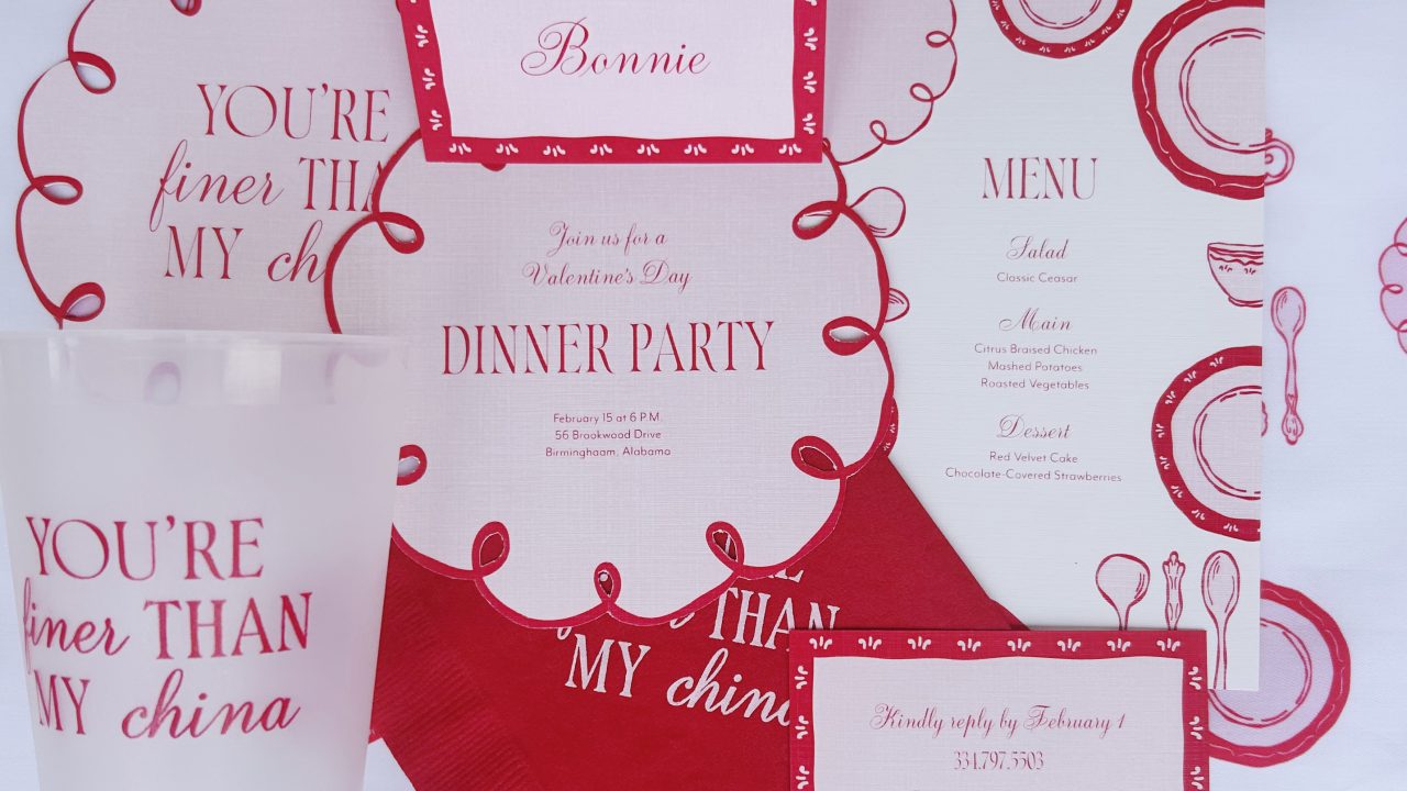 Valentine’s Day dinner party invitation suite with pink and red text, a clear cup, and a napkin, all with a You’re finer than my china motif, on a dish-patterned background.