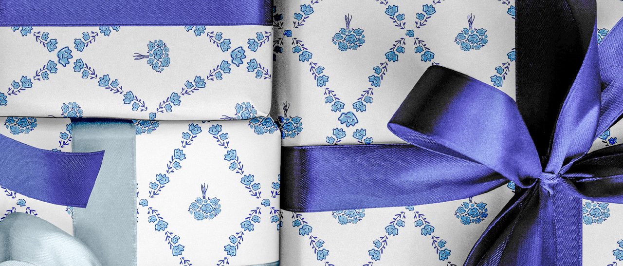 Several gifts are wrapped in white paper with blue floral patterns and decorated with blue and purple satin ribbons.