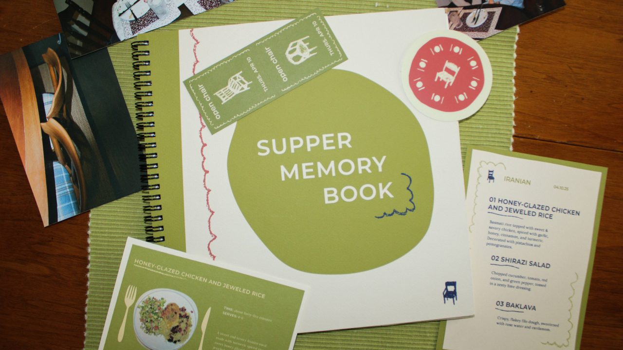 A Supper Memory Book with recipe cards, tickets, a menu, and photos are arranged on a green placemat on a wooden table.