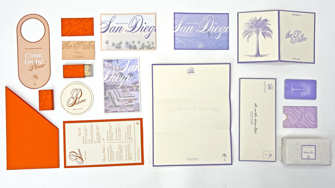 A flat lay of assorted stationary and print materials for The Palm Hotel, including menus, invitations, cards, and envelopes in orange, cream, lavender, and purple tones.