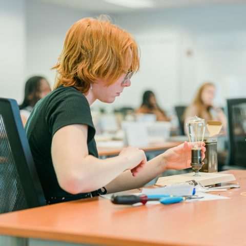 BSCI student, Kathryn McEniry, wiring a lightbulb when she attended Construction Management Summer Academy for Young Women