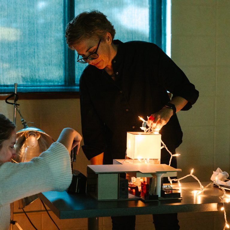 Jennifer Pindyck assists a student in studio during a lighting fixture project.