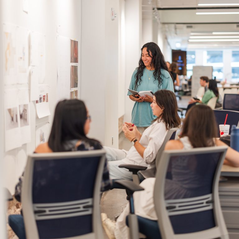 Professionals share practical feedback with students during a design studio critique.