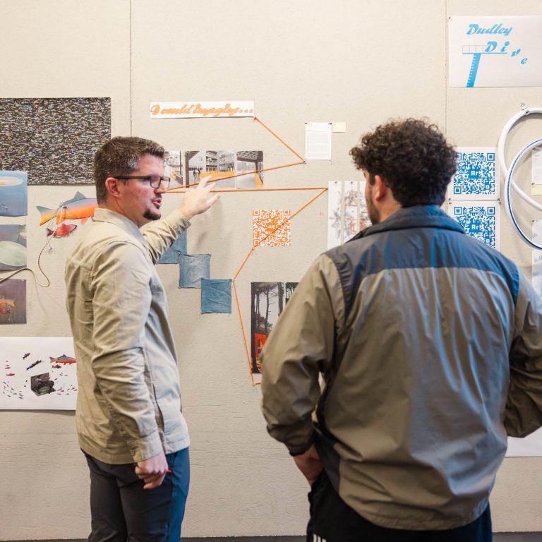 Bird offers feedback to an APLA student during a pin-up review in a studio. 