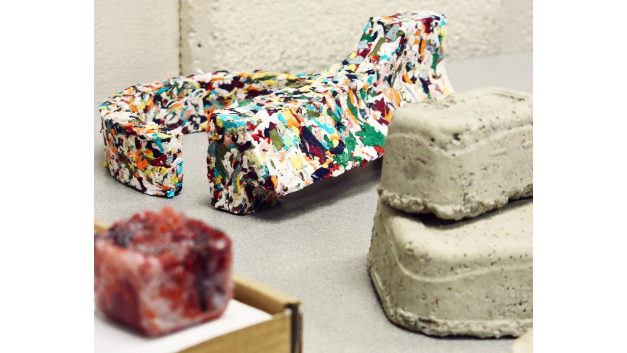 Auburn University Environmental Design student work Several colorful and neutral-toned sculptural objects made from upcycled materials are displayed on a tabletop against a white wall.