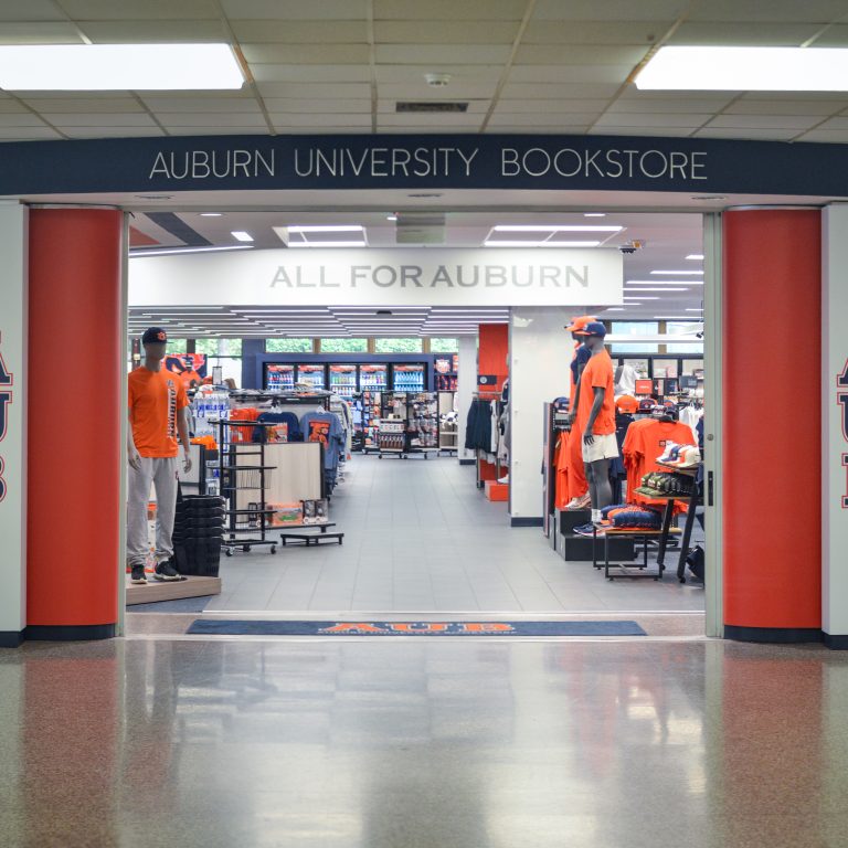 Entrance to the Auburn University Bookstore with merchandise displays and mannequins dressed in Auburn apparel visible inside.