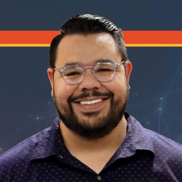 A person with short dark hair, glasses, and a beard is smiling in front of a geometric background with orange and yellow borders.