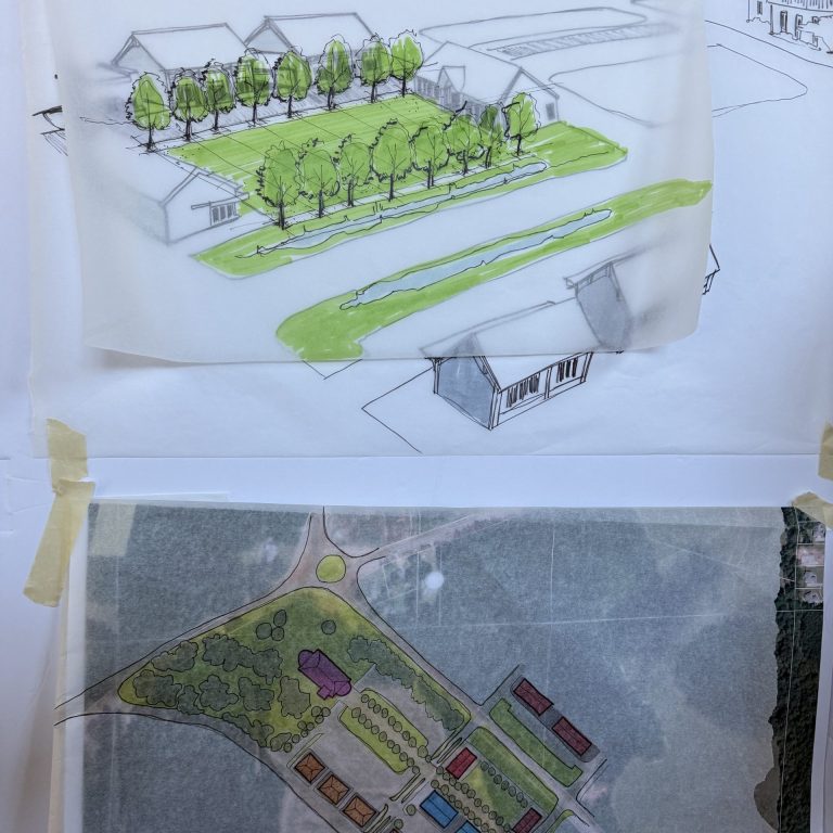 Two architectural site plans taped to a wall: the top shows a perspective drawing with trees and buildings, while the bottom shows a colored overhead layout of a property with multiple structures.