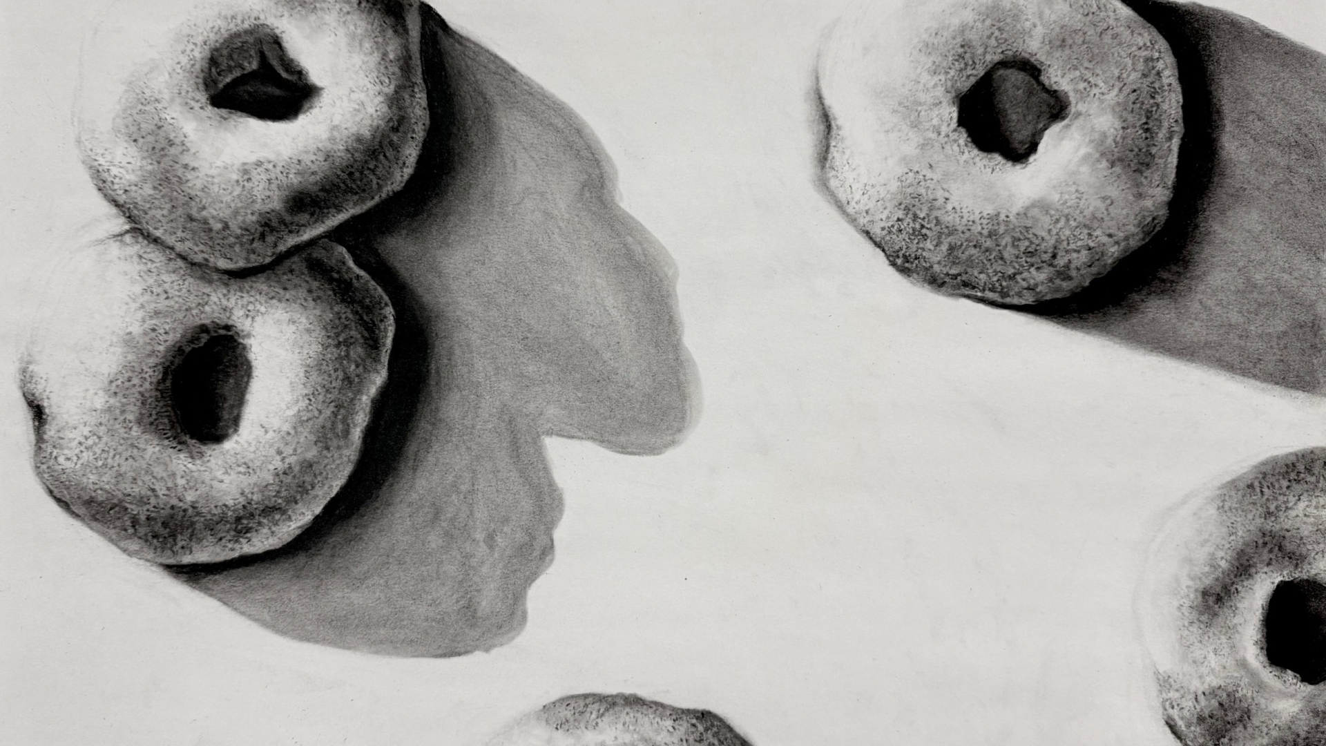A realistic pencil drawing of five bagels casting shadows on a flat surface, with light coming from the upper left.