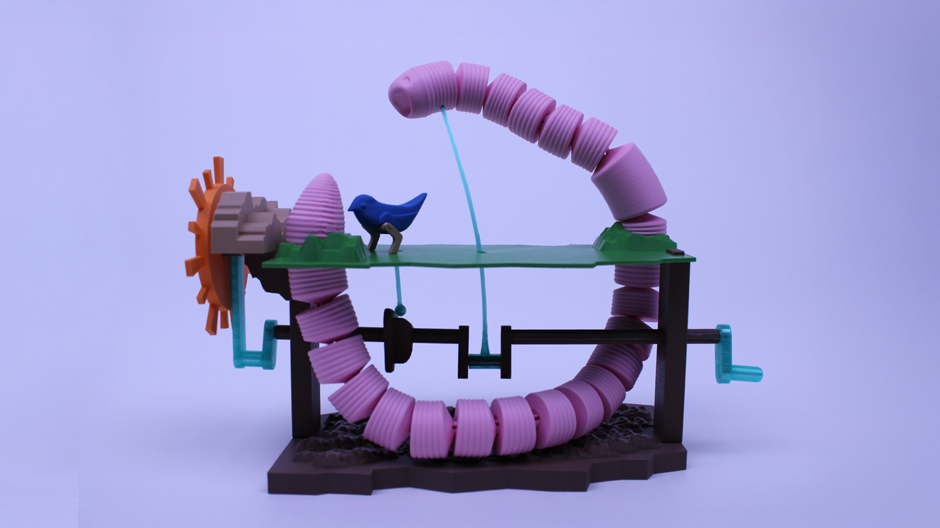 A plastic model featuring coiled pink tubes, a blue bird, a gear, and green platforms, arranged in a mechanical, abstract assembly on a purple background.