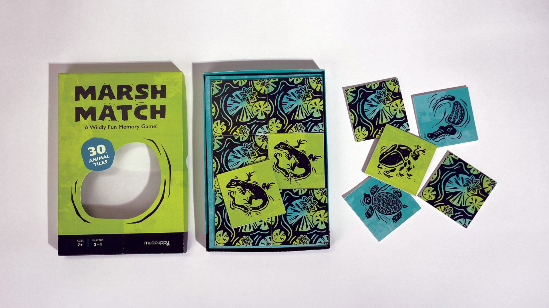 A memory game called Marsh Match with box, illustrated instruction booklet, and several animal-themed matching cards laid out on a white surface.