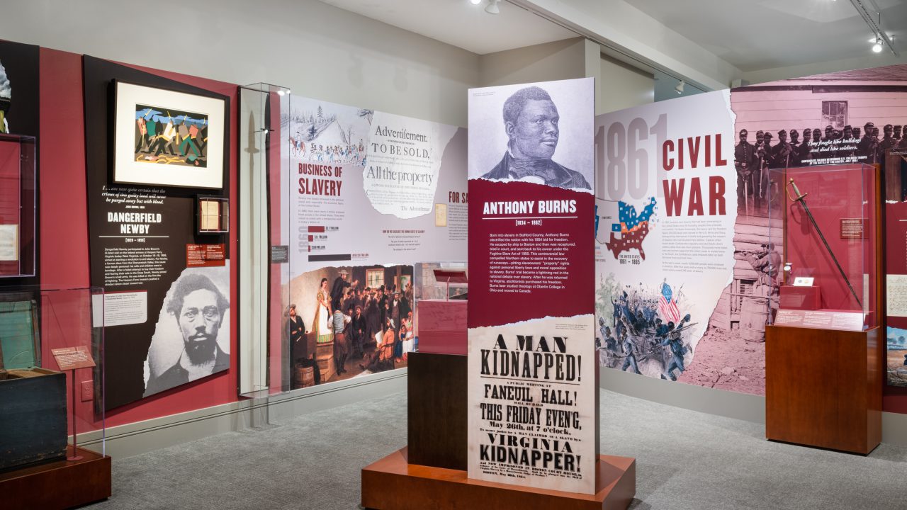 Museum exhibit on the history of slavery, featuring artifacts, photographs, and informational panels about Anthony Burns, the Civil War, and abolitionist movements.