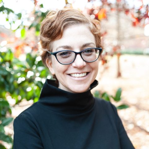A woman with glasses smiling.
