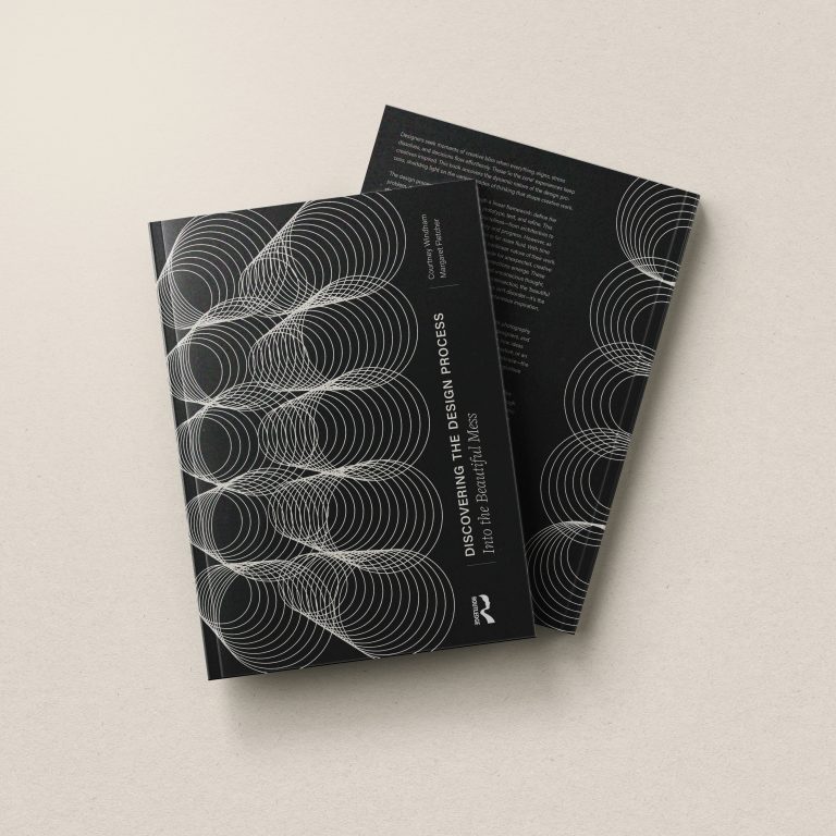 Two black books with white, concentric circle designs on the covers are arranged on a light beige surface, one book stacked slightly over the other.