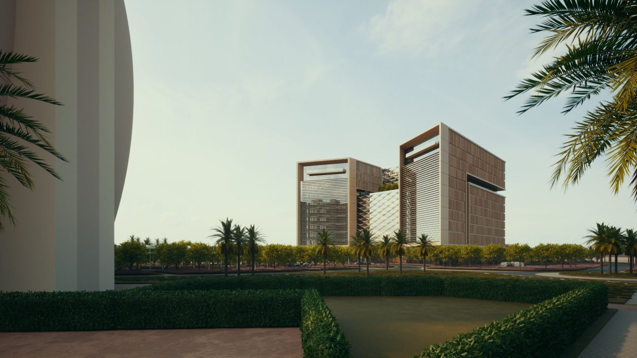 Modern office buildings with large rectangular frames, surrounded by palm trees and greenery under a clear sky.