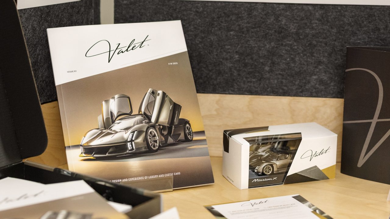 A display of branded materials including a brochure, box, keychain, and printed cards, all featuring the Valet logo and images of a luxury sports car.