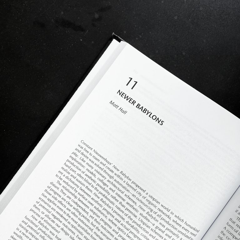 Open book showing chapter 11 titled Never Babylons by Matt Hall, with a portion of text visible on a black surface.