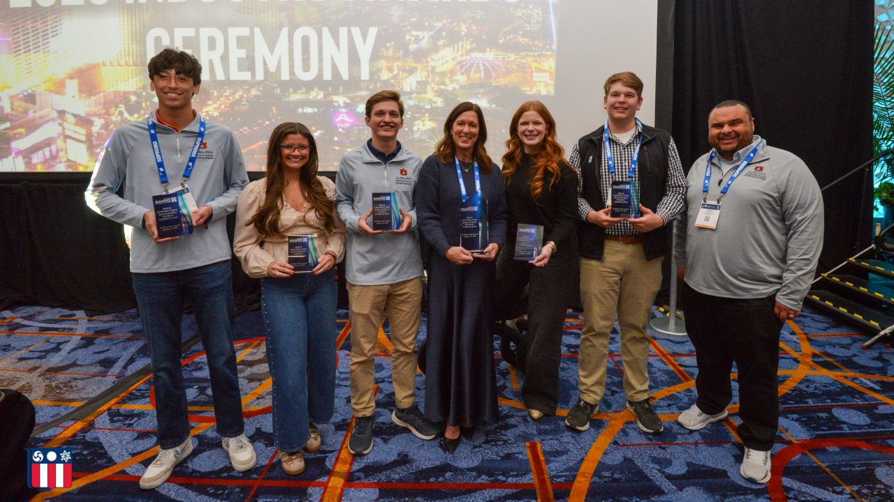 Seven people stand in front of a screen displaying 2026 Industry Awards Ceremony, holding awards and smiling at the camera.