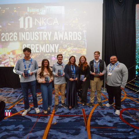 Seven people stand in front of a screen displaying 2026 Industry Awards Ceremony, holding awards and smiling at the camera.