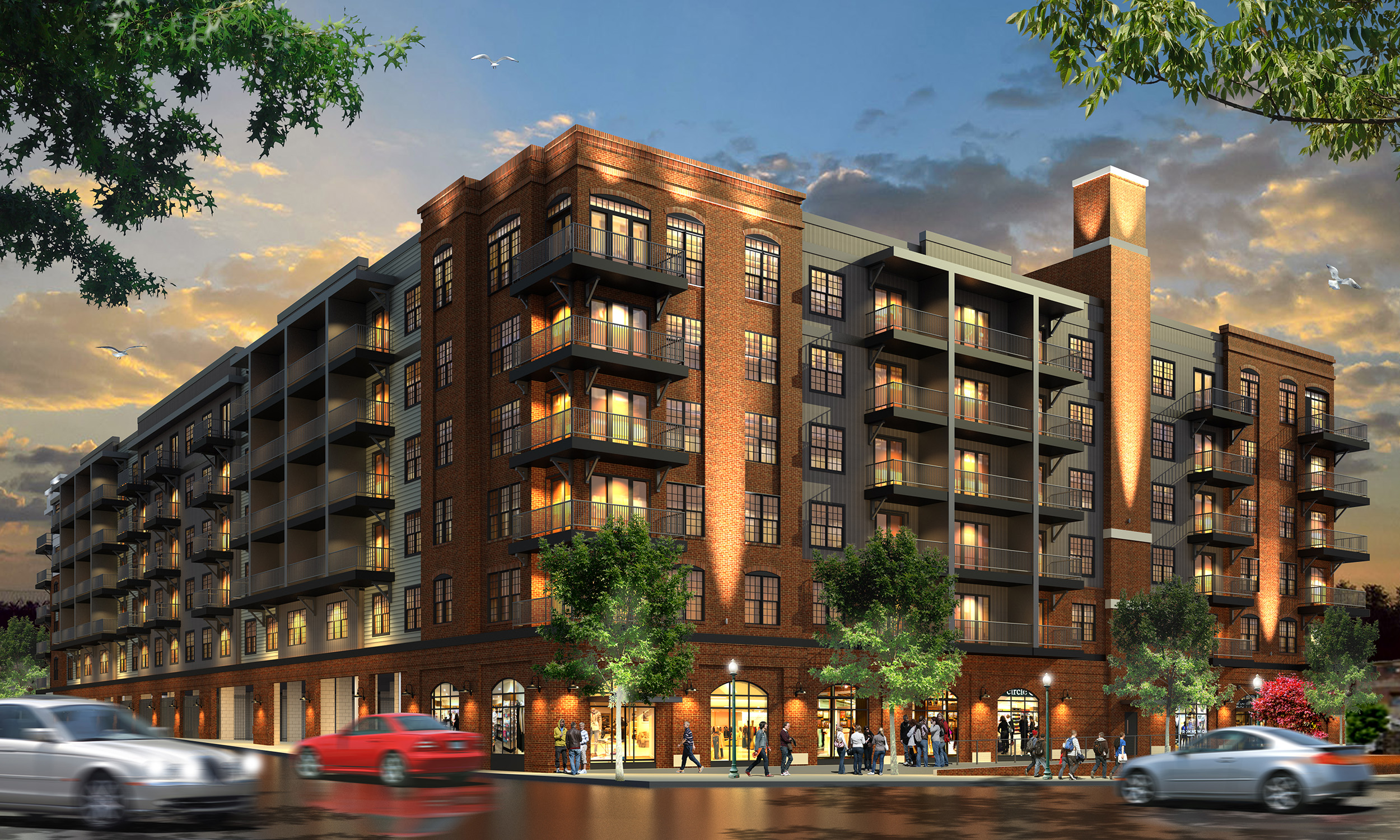 A five-story brick apartment building with balconies, large windows, and ground-floor retail, set along a busy street with cars and pedestrians in the evening.