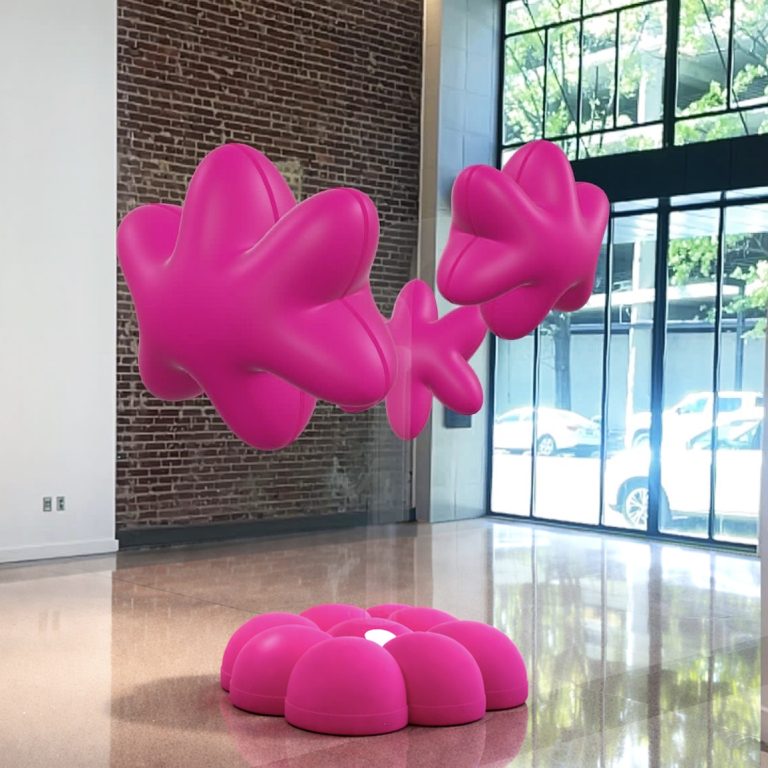 Three large, pink, abstract balloon-like sculptures hover above a matching pink cushion in a modern room with brick and glass walls.