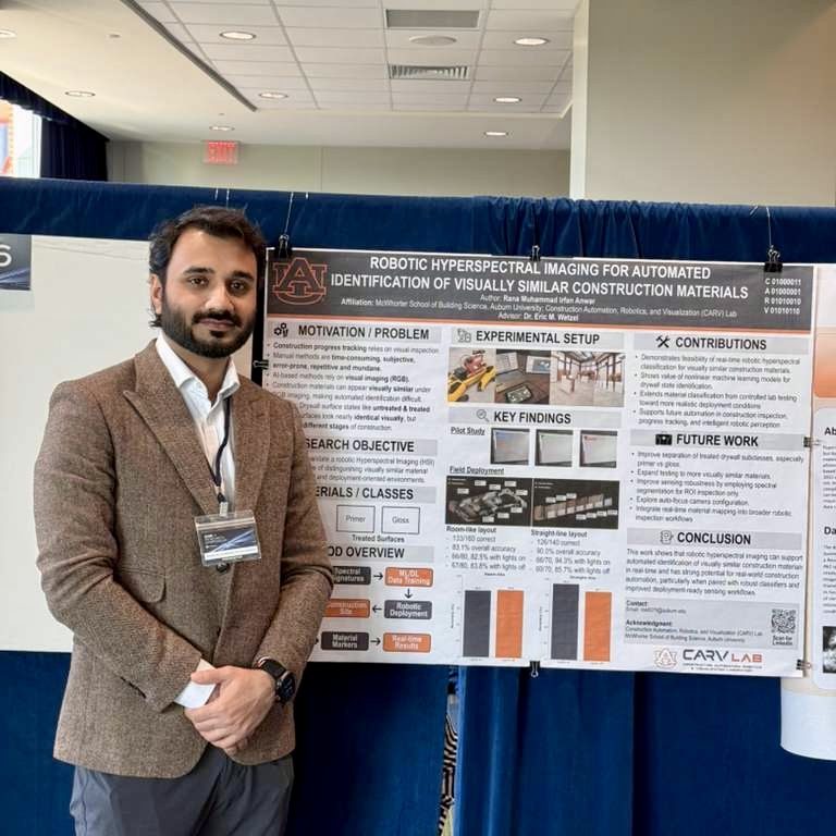 A man in a brown blazer stands beside a research poster on robotic hyperspectral imaging for construction materials at a conference.