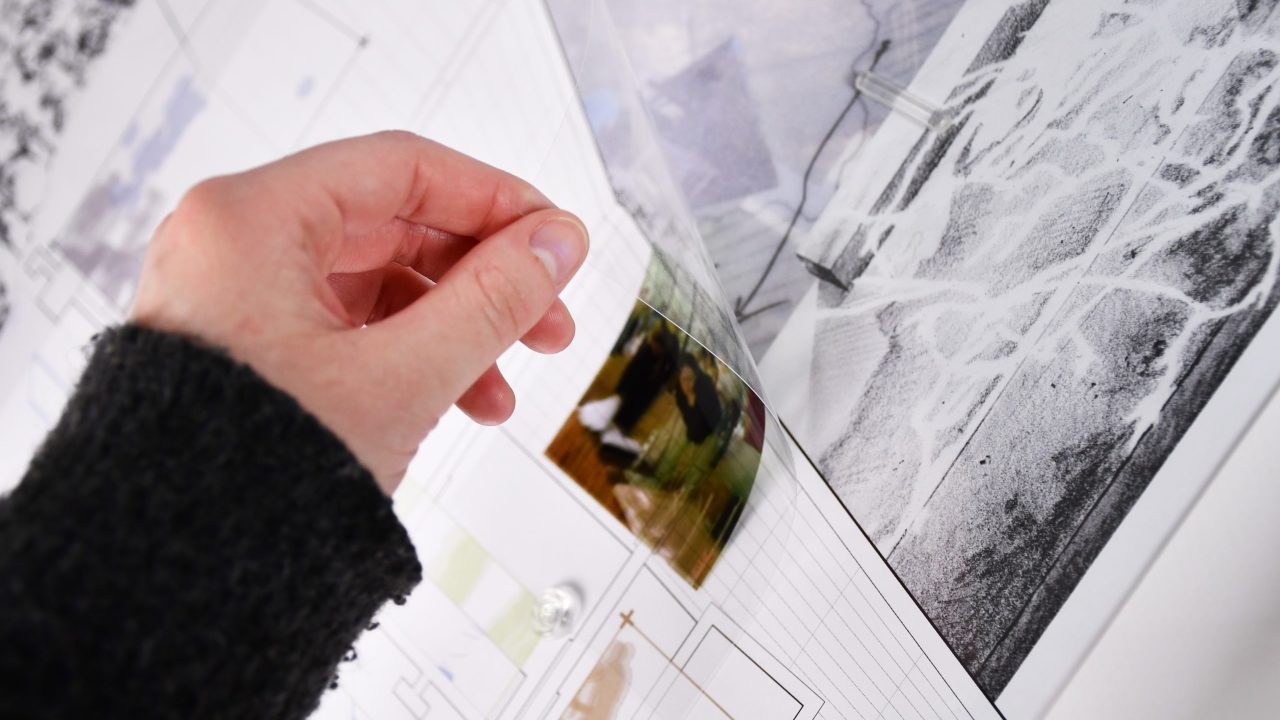 A hand lifts a transparent sheet over architectural plans, revealing a color photo underneath on a white background.