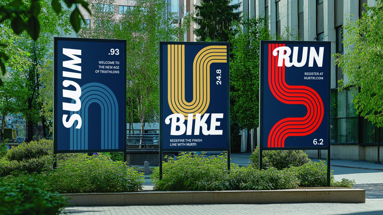 Three outdoor signs display the words Swim, Bike, and Run with respective numbers 0.93, 24.8, and 6.2, promoting a triathlon event in a city setting.