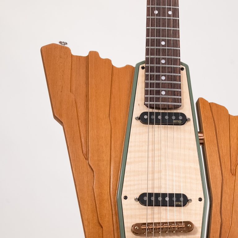 Close-up of an electric guitar with a uniquely shaped wooden body, featuring dual humbucker pickups and a natural wood finish.