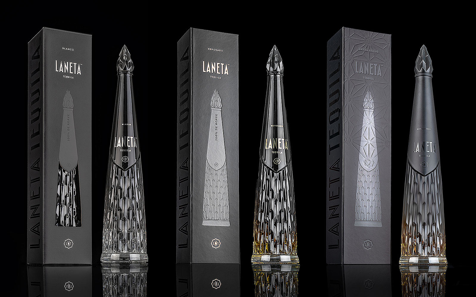 Four tall, intricately designed Laneta Tequila bottles stand in front of matching black and silver packaging boxes against a black background.