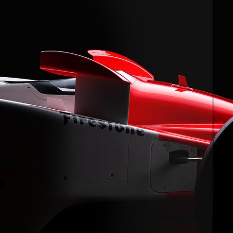 A magazine spread shows a close-up side view of a red and white race car on the left page, with text and a quote on a black background on the right page.