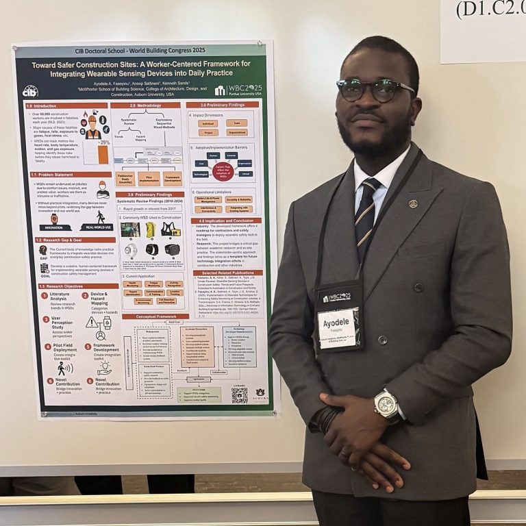A man in a suit stands next to a research poster displayed on a whiteboard at a conference or academic event.