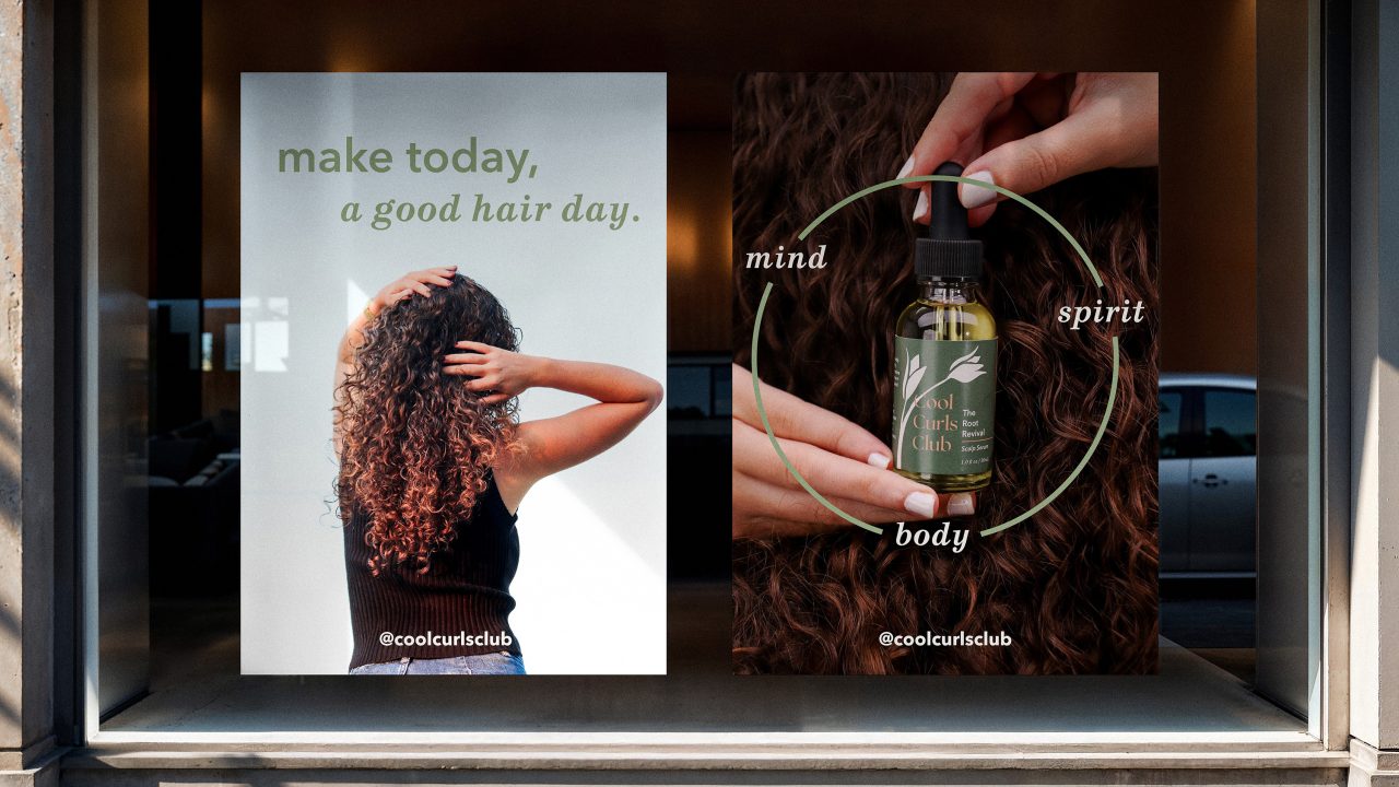 Two posters in a store window: one shows a person with curly hair and the text make today a good hair day; the other shows hands holding a hair product labeled “mind, spirit, body.”.