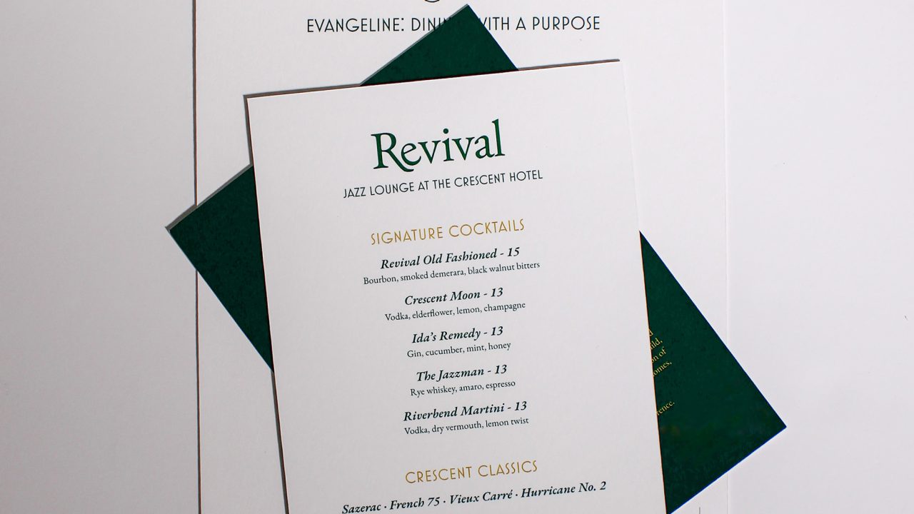 A paper cocktail menu titled Revival rests on top of two stacked event menus on a white background.