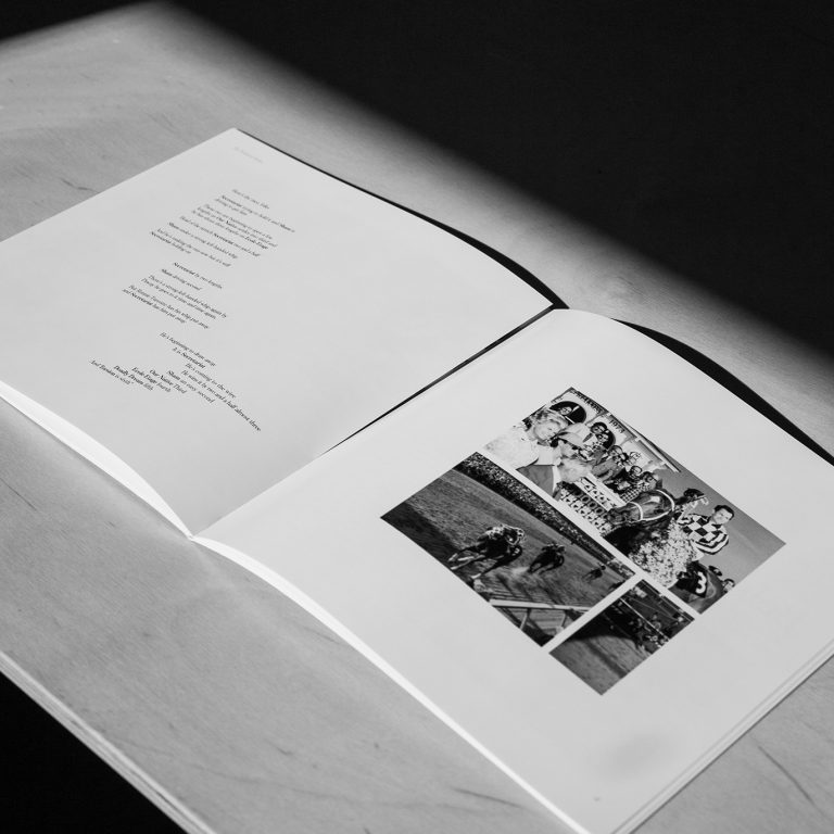 A black-and-white photo of an open book on a table, showing a page with text on the left and several vintage group photos on the right.