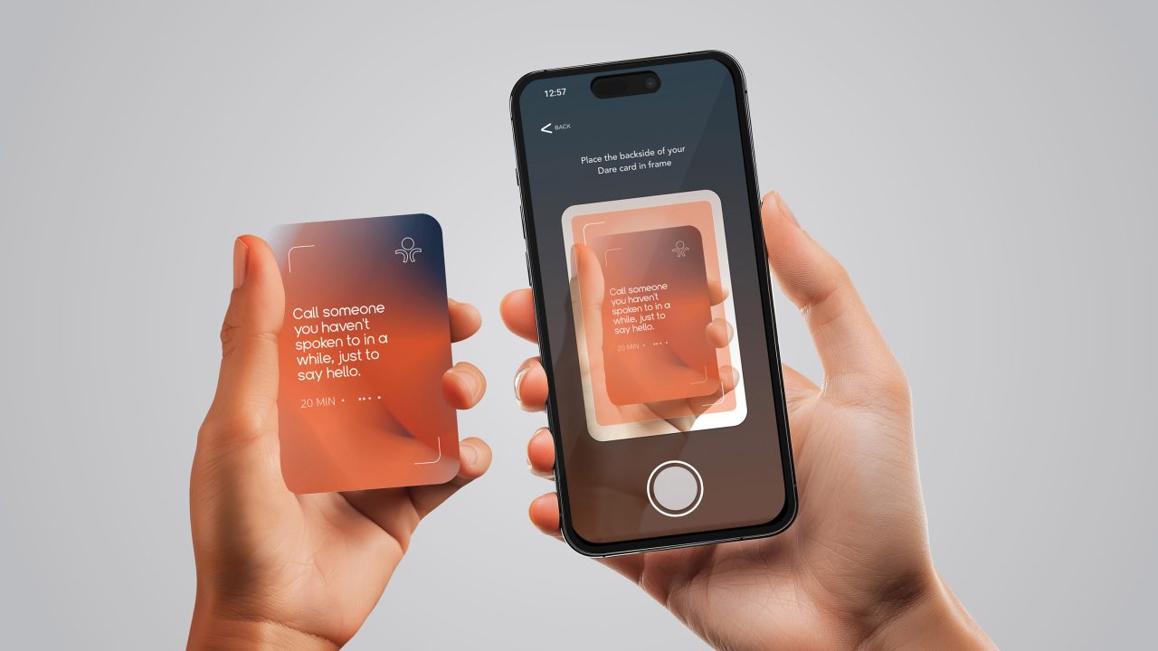 A hand holds a card with text, while another hand scans it using a smartphone camera; the phone screen displays the card’s image and instructions.
