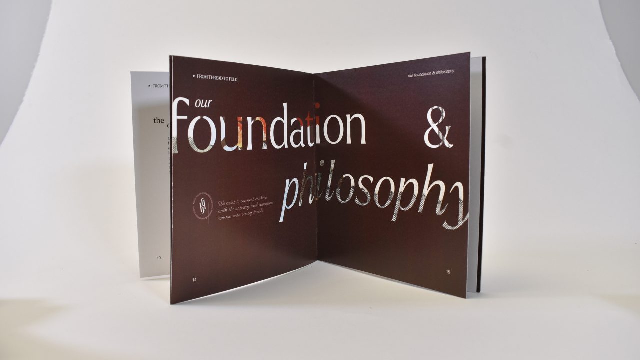 An open book displays the text our foundation & philosophy in large, mixed fonts on a dark page, with a white background behind the book.