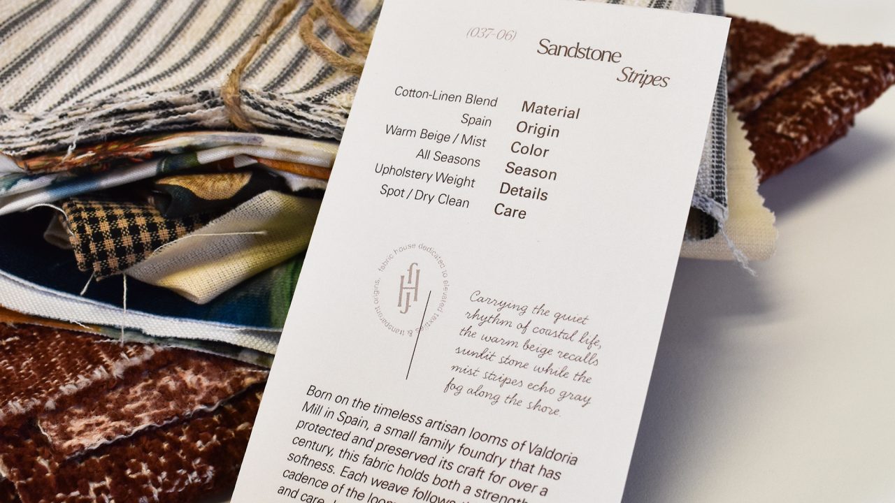 A stack of assorted fabric swatches sits behind a standing card detailing fabric composition, care instructions, and product description.