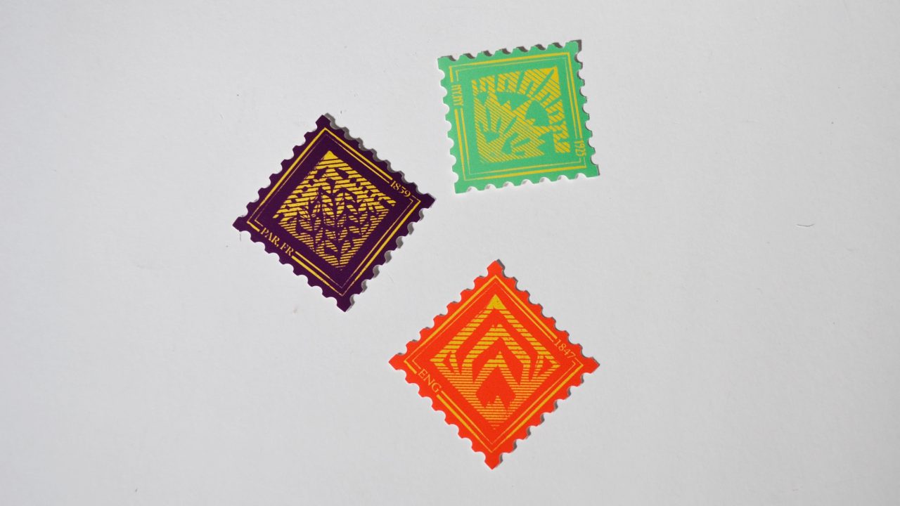 Three diamond-shaped postage stamps in purple, green, and orange, with geometric patterns, are arranged on a white background.