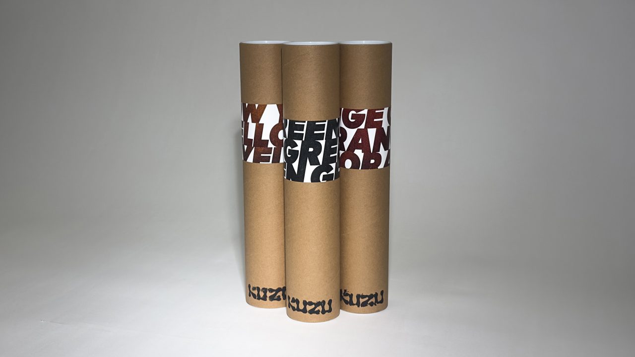Three brown cylindrical tubes with white labels featuring bold, partially visible red and black text, standing upright against a plain background.